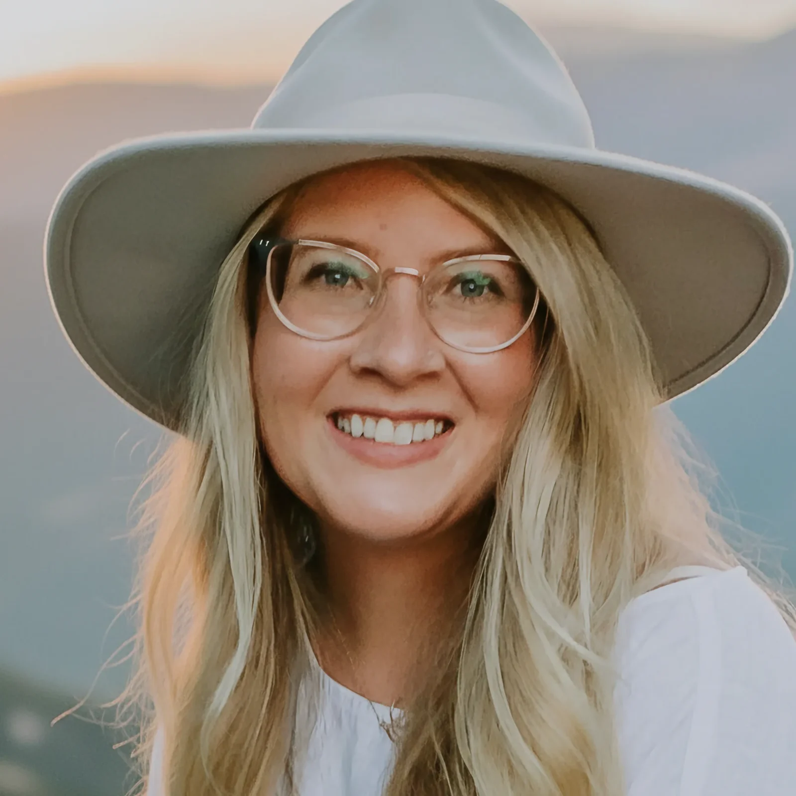 Sara Davenport – A woman smiling with glasses, blonde hair and a hat.